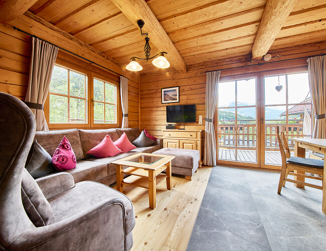 Holz-Wohnzimmer mit Sofa, Balkon und Bergblick.