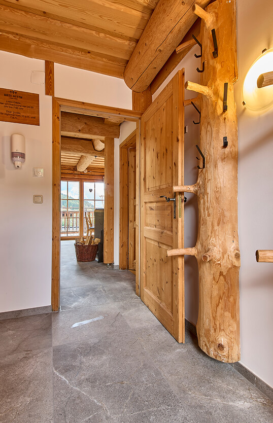 Holzverkleideter Flur mit offener Tür, Baumstamm-Garderobe.