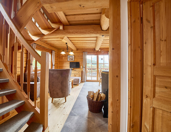 Blockhaus-Wohnraum mit Treppe, Sitzbereich, Bergblick.