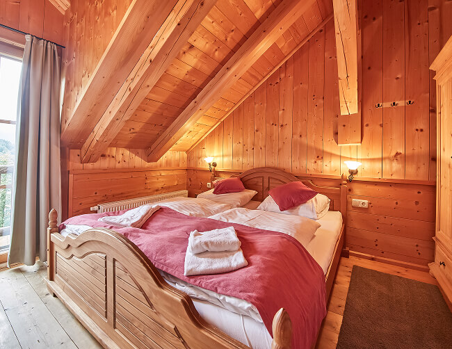 Holzschlafzimmer mit Doppelbett unter Dachschräge.