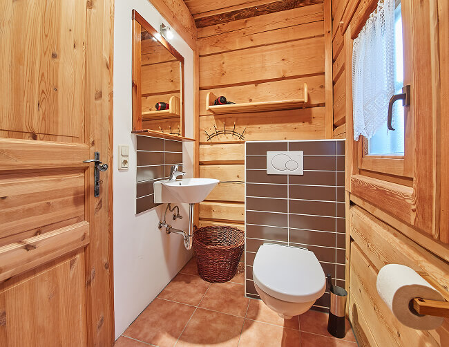 Hölzernes Badezimmer mit Toilette und Waschbecken.