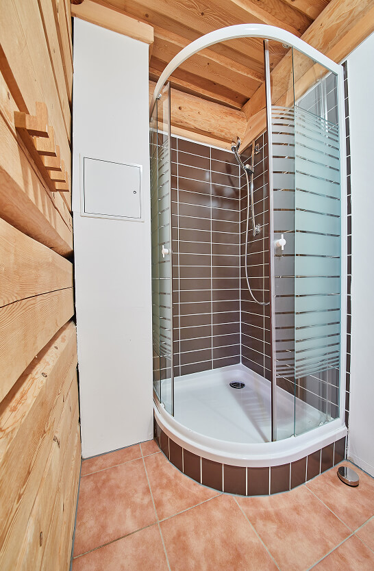 Eckduschkabine mit Holzwänden und braunen Fliesen.