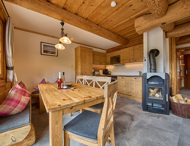 Holzgetäfelte Küche mit Essplatz und Kaminofen.