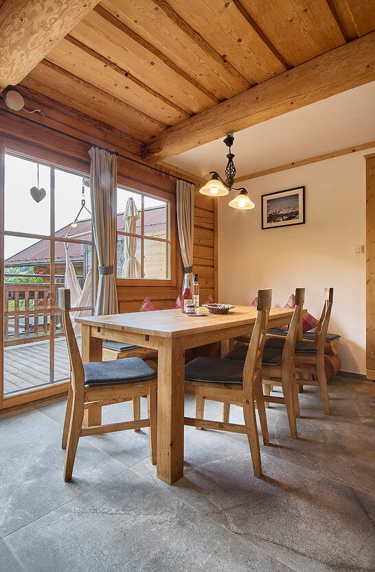 Rustikaler Essbereich mit Holztisch, Stühlen, Balkonblick.