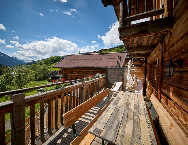 Heller Holzbalkon mit Sitzmöbeln und Bergpanorama