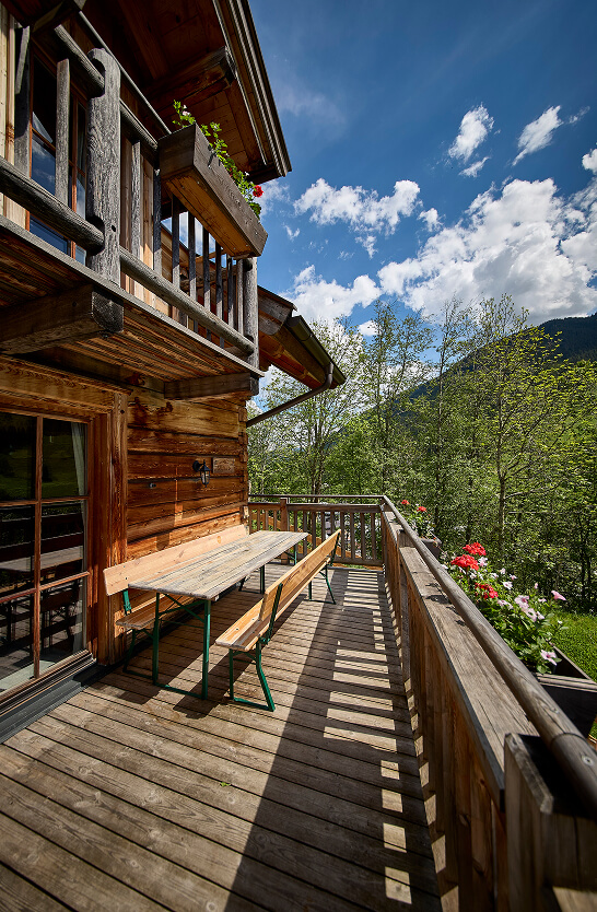 Heller Holzbalkon mit Sitzmöbeln und Bergpanorama