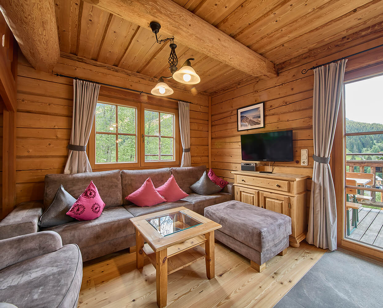 Holzvertäfeltes Wohnzimmer mit Couch, TV und Balkon.