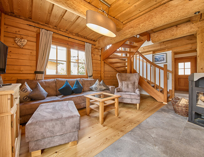 Holz-Wohnzimmer mit Sofa, Sessel, Treppe und Kamin.