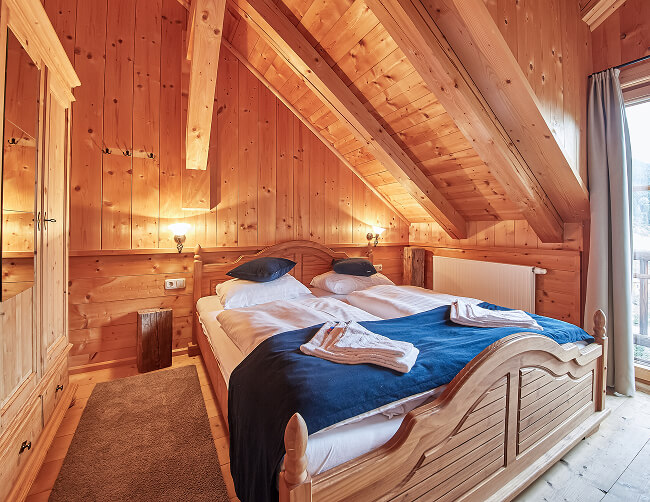 Holzgetäfeltes Dachgeschosszimmer mit Doppelbett.