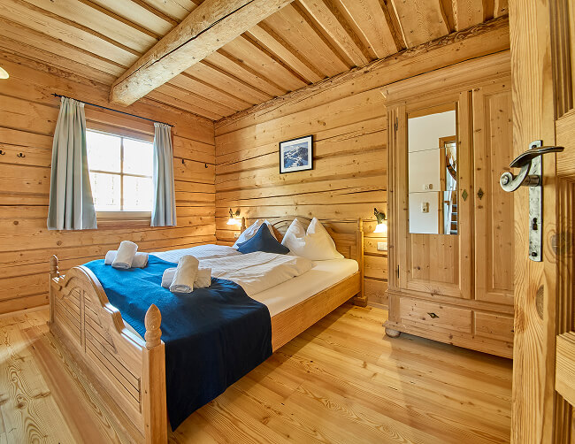 Schlafzimmer aus hellem Holz mit Bett, Schrank, Fenster.