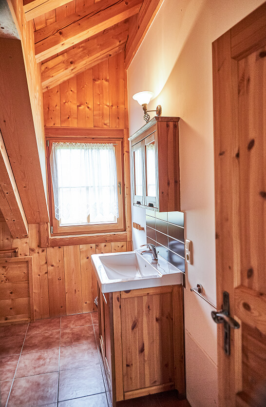 Holzverkleidetes Badezimmer mit Waschbecken und Fenster.