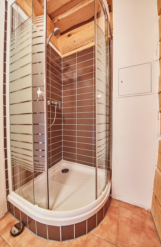 Braune Eckdusche mit gestreiften Glastüren und Holzbalken.