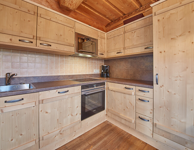 Helle Holzküche mit Geräten und dunkler Arbeitsplatte.