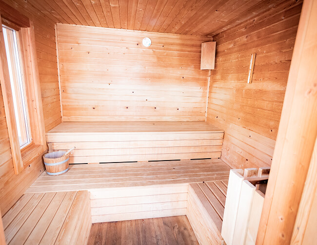 Leere Sauna aus hellem Holz mit Stufenbänken.