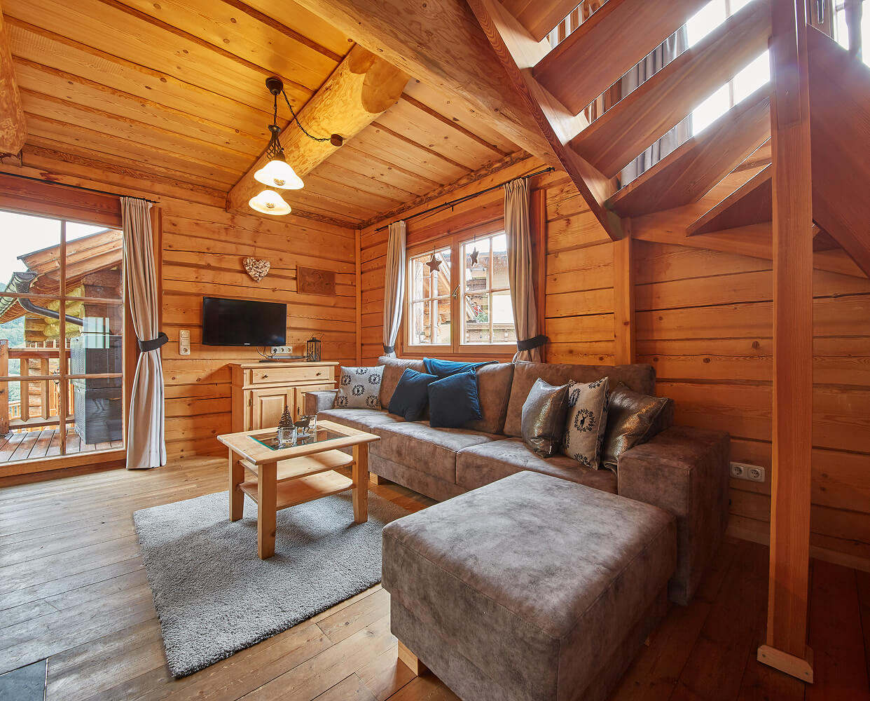 Holzwohnzimmer mit Sofa, TV und Holztreppe.