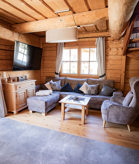 Helles Holz-Wohnzimmer mit Sofa, Sessel und TV.