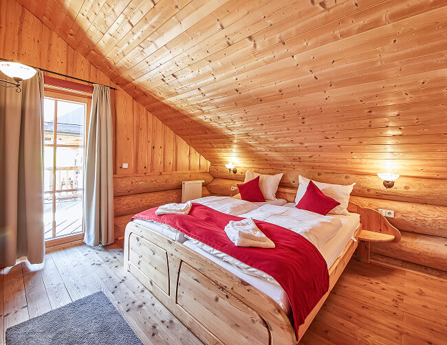 Holz-Schlafzimmer mit Doppelbett und Fenster.