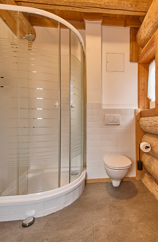 Bad mit Duschkabine, Toilette und Holzbalken.