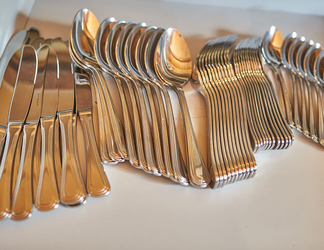Stapel von glänzendem Besteck: Messer, Löffel, Gabeln.