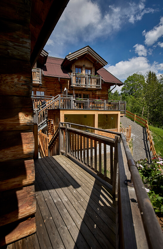 Mehrstöckiges Holzhaus mit Treppen und Balkonen unter blauem Himmel.