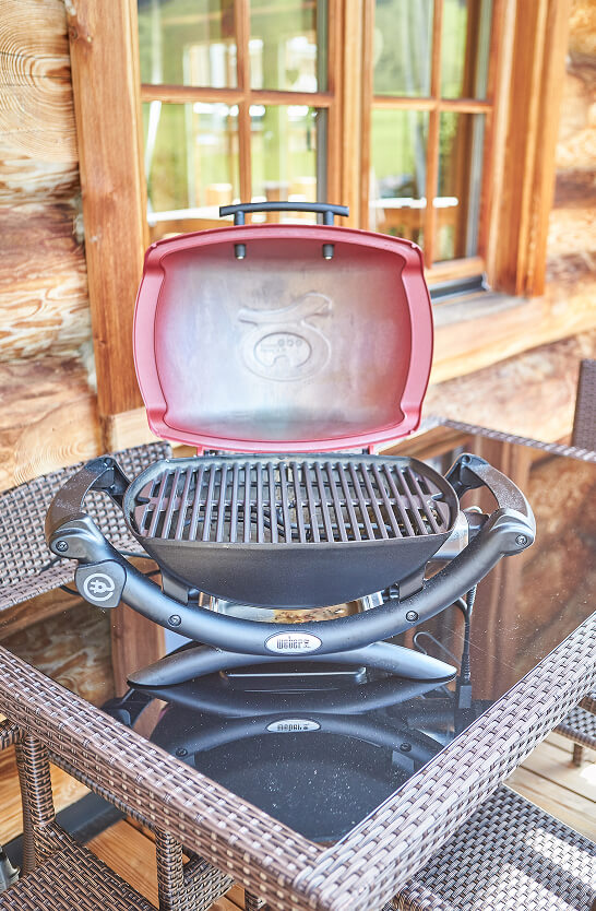 Roter und schwarzer Grill mit offenem Deckel auf Glastisch.