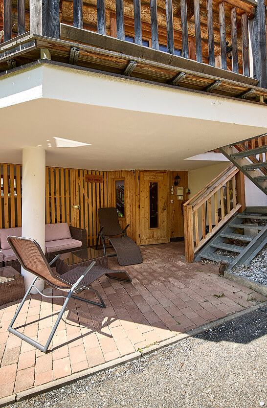 Gepflasterte Terrasse mit Outdoor-Möbeln unter Balkon.