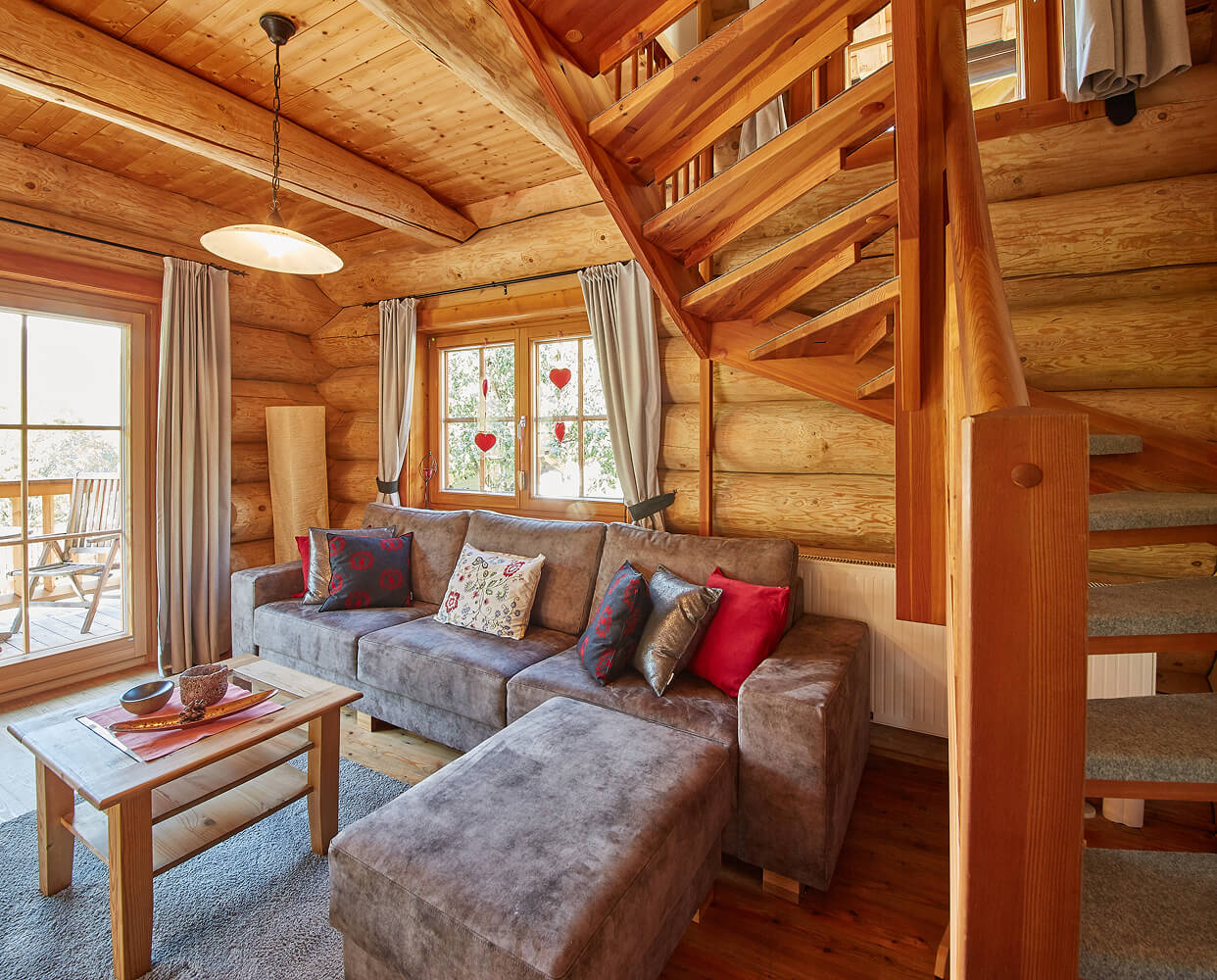 Wohnzimmer im Holzhaus mit Sofa und Wendeltreppe.
