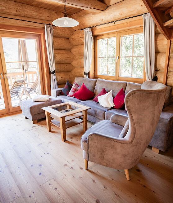 Holzwohnzimmer mit Sofa, Sessel, Couchtisch und Fenster.
