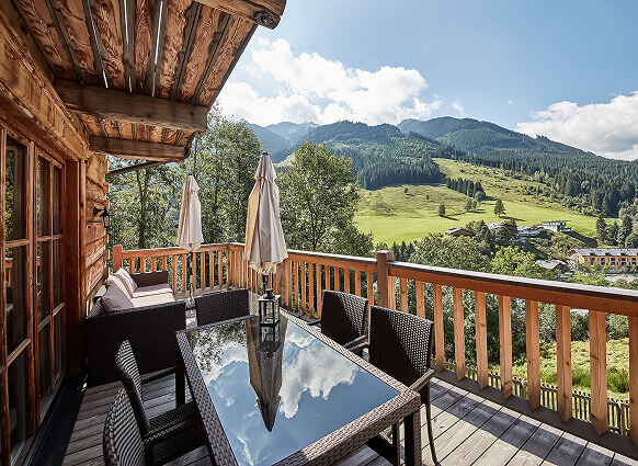 Sonniger Holzbalkon mit Bergblick über Tal und Wiesen.