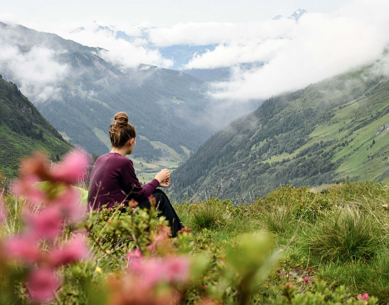 Sitzende Frau auf Bergwiese, Blick ins Tal.