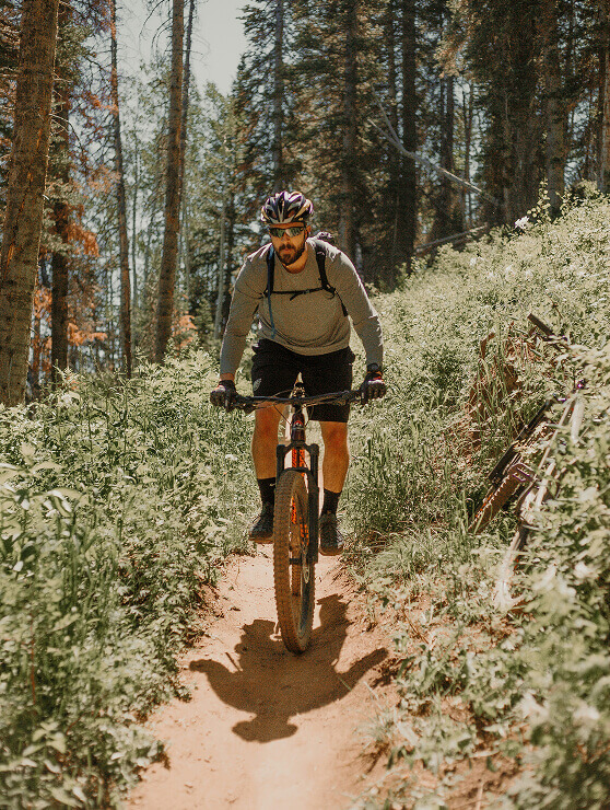 Mountainbiker fährt auf sonnigem Waldweg.