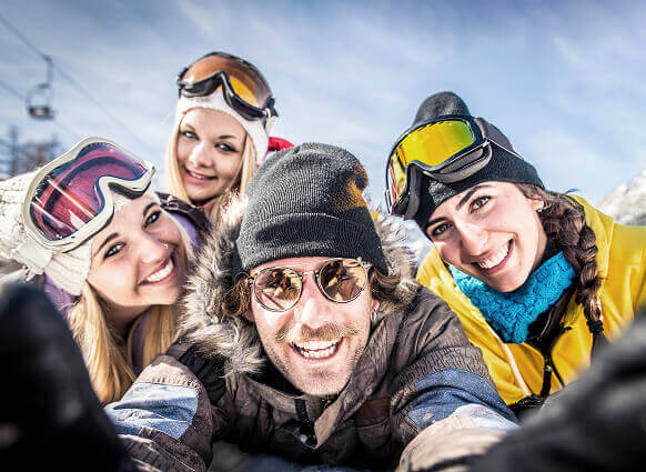 Fünf Personen in Skiausrüstung lächeln in die Kamera.