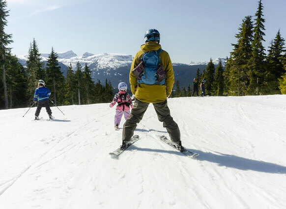 Familie beim Skifahren auf sonniger Skipiste.