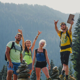 Vier Wanderer posieren lachend auf Felsen am Berg.