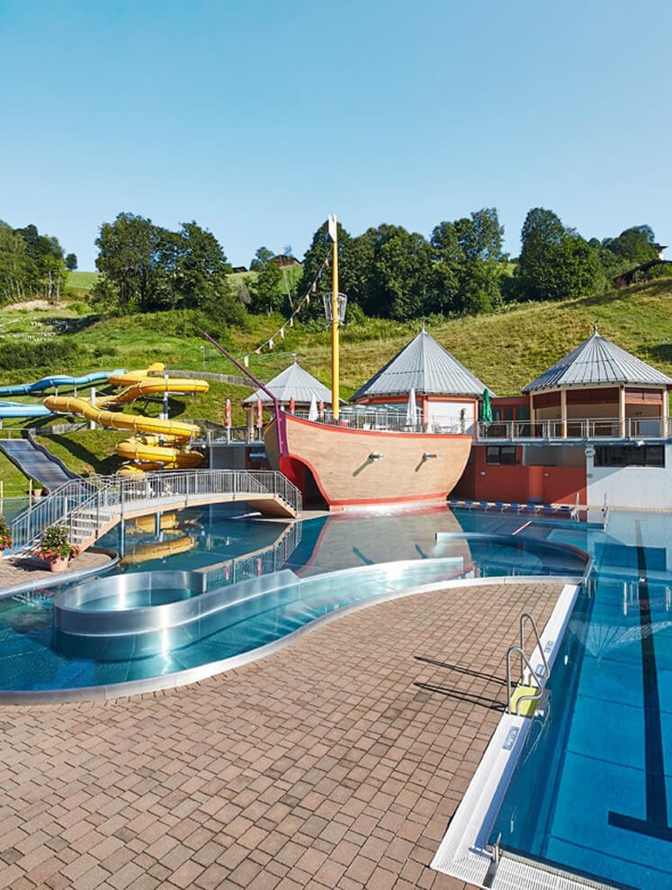 Freibad mit Holzschiff, Wasserrutschen, Pools.