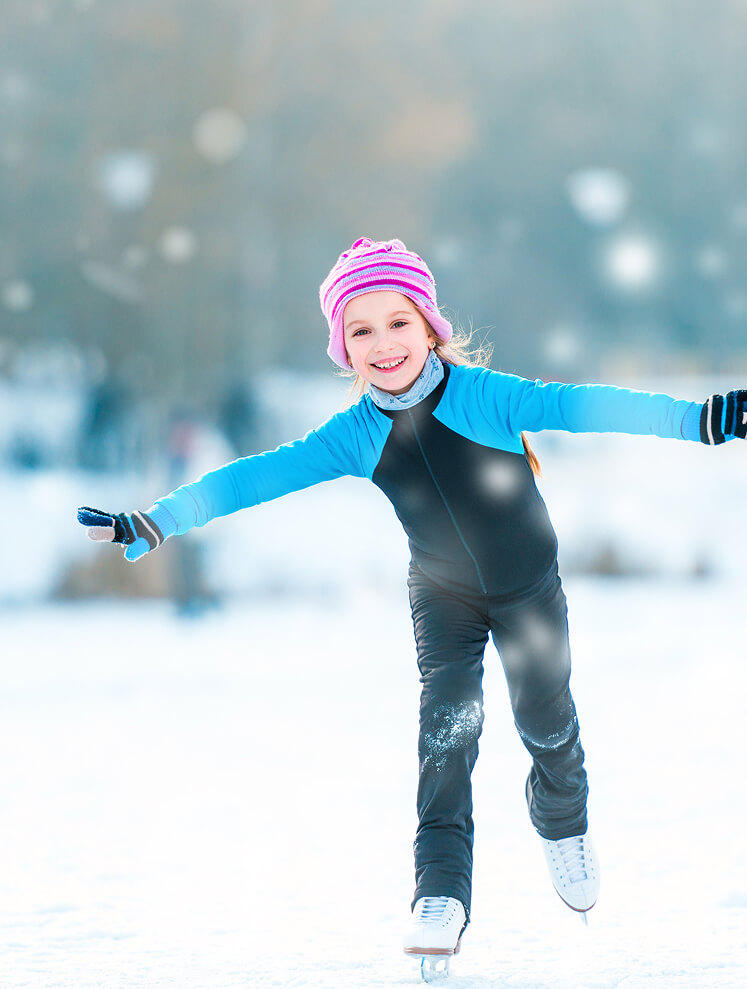 Lachendes Mädchen mit Mütze eislaufend auf dem Eis.