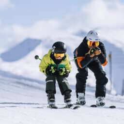 Zwei Skifahrer in Hocke auf verschneiter Piste.