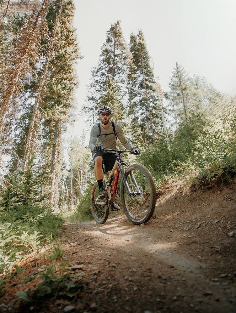 Mountainbiker fährt auf unbefestigtem Weg im Wald.