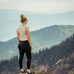 Frau blickt von Felsen auf Bergpanorama.
