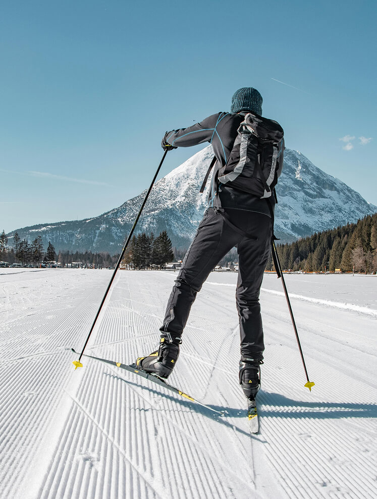 Person beim Langlauf auf Loipe vor Schneeberg.