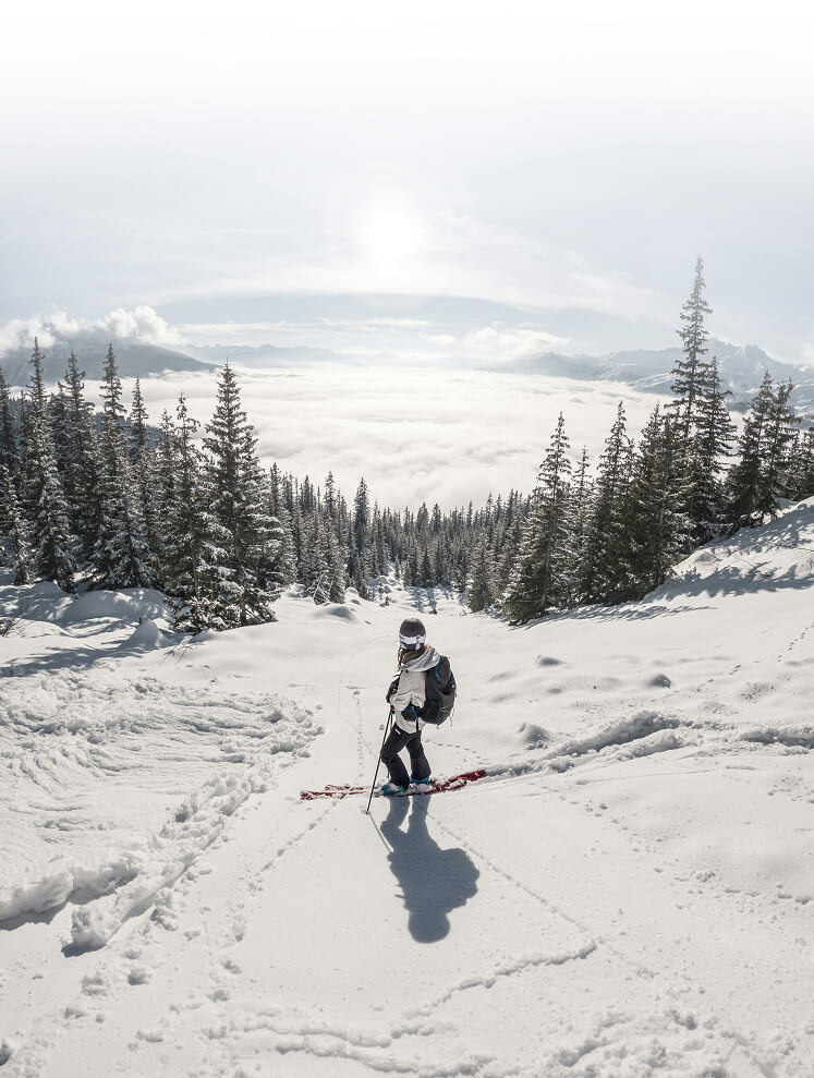 Skifahrer auf verschneitem Hang über Wolkenmeer.