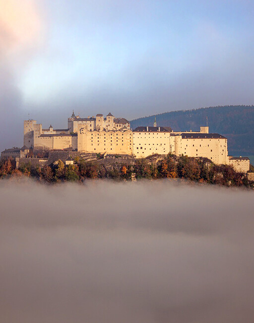 Burg auf Hügel über einer dichten Nebelbank.