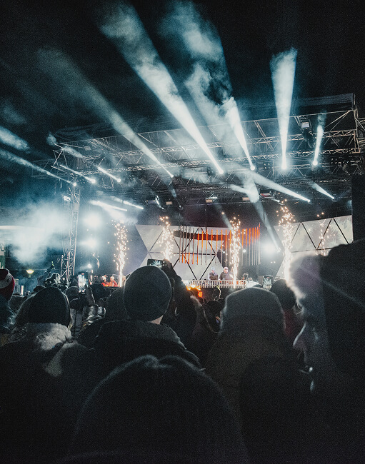 Konzertbühne bei Nacht mit Lichtern, Funken und Publikum.