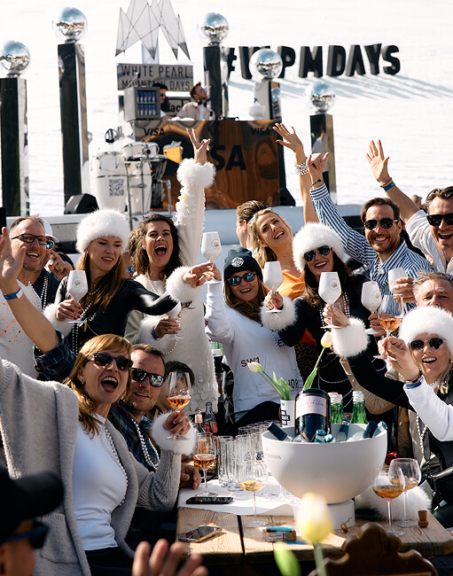 Gruppe jubelt mit Gläsern auf winterlicher Außenparty.