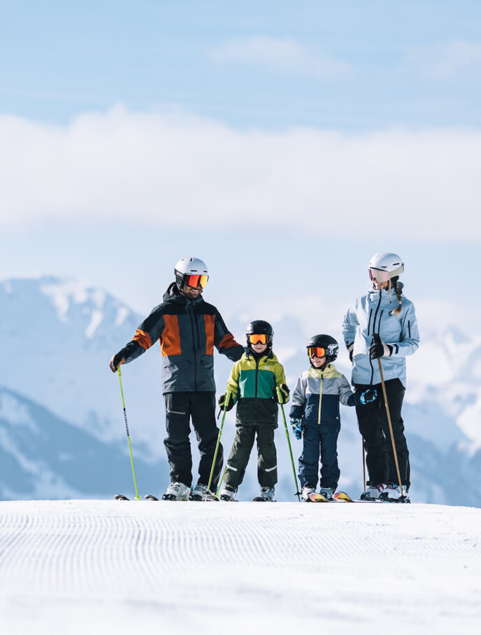 Vierköpfige Familie in Skiausrüstung auf Piste.